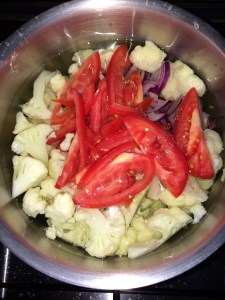Add the cut pieces of cauliflower, onions, tomatoes and green chili.