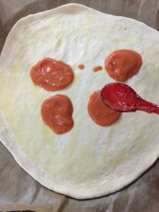 Now add a 2 tbsp of pizza sauce over the pizza. Spread it evenly.